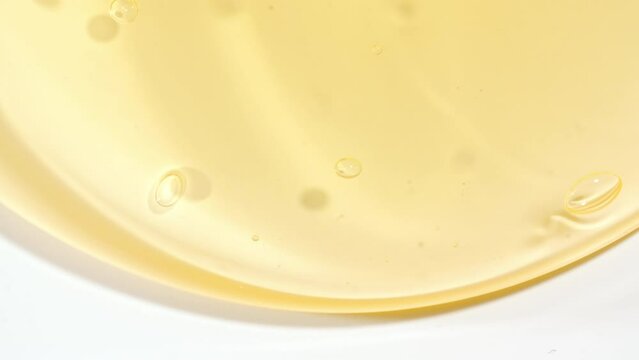 Macro Shot of Transparent Yellow Cosmetic Fluid Gel, Cream With Bubbles Flowing down on a White Surface. Natural Organic Cosmetics, Medicine. High quality 4k footage
