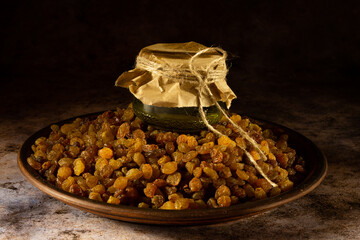 Dried raisins on a black background and olive oil in a glass container