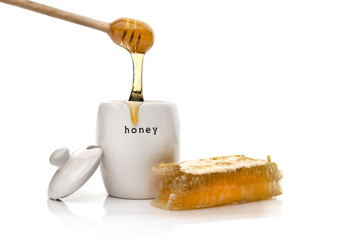 Honey and jar with a wooden dipper isolated on a white background