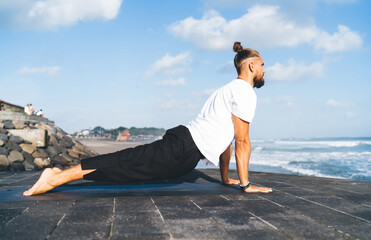 Caucasian guy doing asana during retreat yoga practice keeping mental and physical strength,...