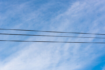Wires against the blue sky with clouds. Three wires. - Powered by Adobe