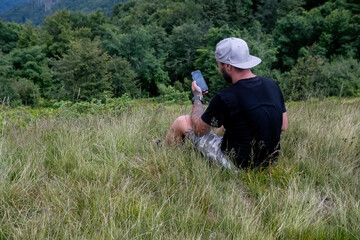 Naklejka na ściany i meble Man using smartphone hike in mountains travel blogger influencer lifestyle adventure vacations summer tour outdoor in Norway