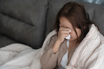 Asian sick woman sit on the sofa stay at home,The woman felt bad, wanted to lie down and rest,high fever