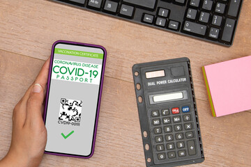 A woman's hand holds a mobile phone with an application international covid 19 certificate