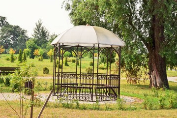 beautiful openwork arbor in the park in spring early morning