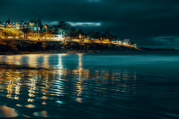 Naklejka premium cape with hotels and reflection in the sea at night