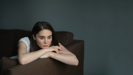 Pensive girl sitting on the couch