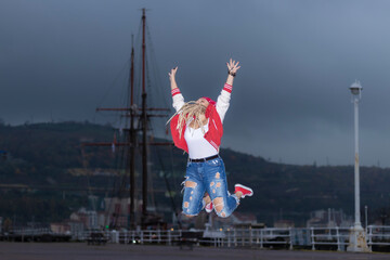 blonde woman with dreadlocks jumping on a cloudy day