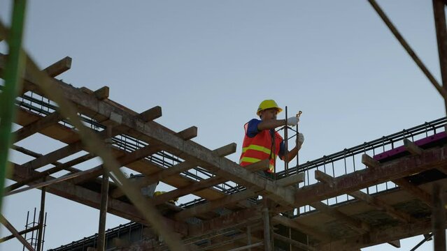 Construction workers working on scaffolding work at risky heights. Steel binding wire strengthens the structure before the columns are poured.
