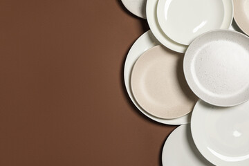 Different plates on brown background, flat lay. Space for text