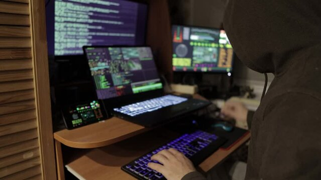 a hacker in a dark room in front of a monitor is trying to hack the security system