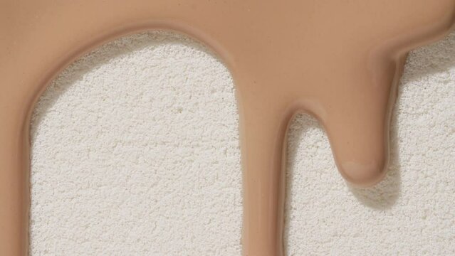 Foundation for face, smear, concealer, cosmetic liquid foundation, or cream beige color smudge flowing down on sponge. Beauty skincare sample. Macro Shot. Close up. High quality 4k footage