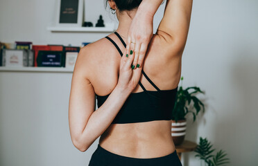 Close Up Photo of An Anonymous Woman Stretching Arms and Shoulders in the Morning. 
Rear view of unrecognizable woman practicing yoga at home,  holding hands behind back in cow face pose. 