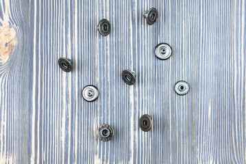 Buttons for jeans on a wooden table.