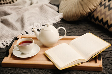 Comfortable place for reading with open book and hot tea - obrazy, fototapety, plakaty