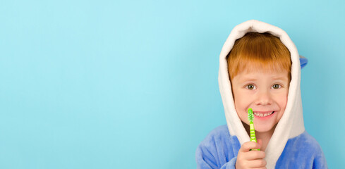 Blank for advertising toothpaste. A four-year-old boy in a bathrobe and a toothbrush in his hands looks at the camera and smiles.