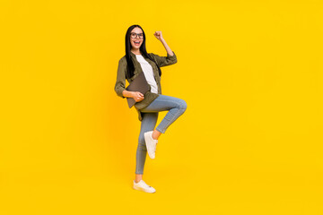 Fototapeta na wymiar Full size photo of pretty young lady hold laptop yell wear spectacles shirt jeans shoes isolated on yellow background