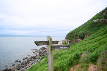 Signpost direction for guiding along walking path, car park, sea and hill beautiful green nature scenery.