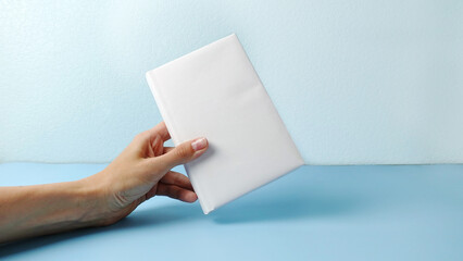A mockup of an close book in womans hand isolated on blue .mockup with shadow. book endpaper. Blank catalog, magazines or brochure.