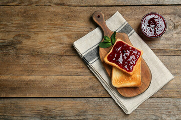 Delicious toasts served with jam and mint on wooden table, flat lay. Space for text
