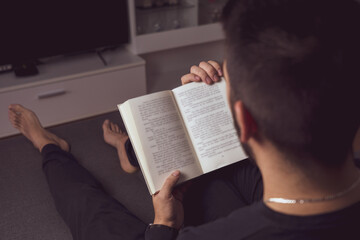 Naklejka premium Unrecognizable young boy reading a book in his home