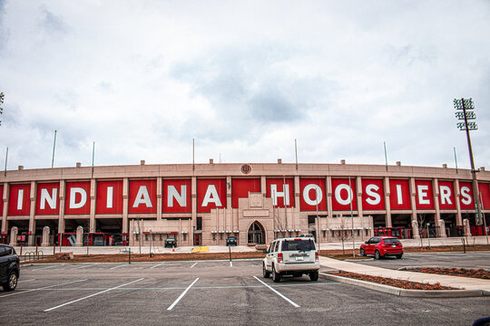 2021-03-26-Bloomington Indiana USA - Side View Of Hoosier Indiana Football Stadium And Ticket Offices With Parking Lot In Foreground And A Few Parked Cars - Copy Space.