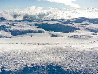 Mountain peak covered with snow. Winter in the mountains, drone shot. Clouds above the mountain.