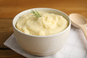 Freshly cooked homemade mashed potatoes, napkin and spoon on wooden table, closeup