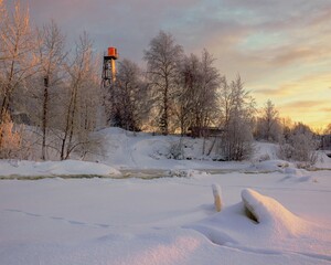 View of the winter bank of the river with a lighthouse among the trees. Travel concept
