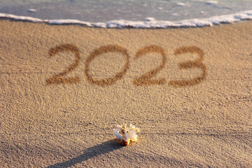 Ein Sandstrand mit Meer und Muschel mit der Jahreszahl 2023