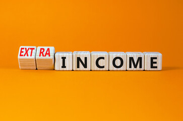 Extra income symbol. Turned wooden cubes and changed concept words income to extra income. Beautiful orange table, orange background copy space. Business and extra income concept.