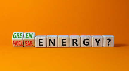 Nuclear or green energy symbol. Turned wooden cubes and changed concept words nuclear energy to green energy. Beautiful orange background copy space. Business nuclear green energy concept.