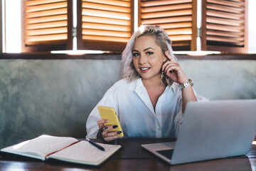 Portrait of skilled female copywriter with laptop and textbook for planning holding modern...