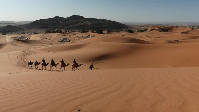 Group of tourists on a camel caravan in the desert in Morocco.