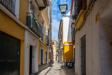One of the typical narrow streets of shops and cafes in the Andalusian city of Seville, Spain.