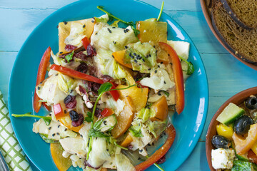 Salad with chicken and cheese, with herbs, persimmons, bell peppers. The concept of diet food. Delicious salad in a bowl on a wooden background, selective focus.

