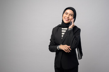 Obraz na płótnie Canvas Portrait of beautiful woman with hijab using cellphone on white background