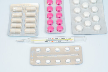 Medical pills with thermometer and capsules in a blister pack isolated on white background
