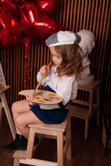 a child in an artist's valentine's costume interferes with the paint on the palette against the...
