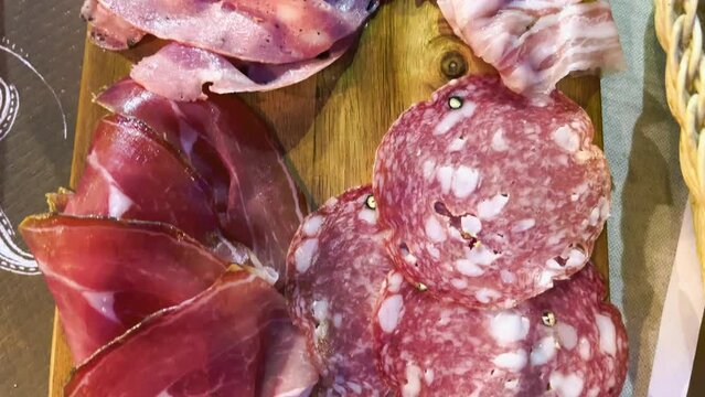 Salami and ham on a wooden tray, classic italian antipasto