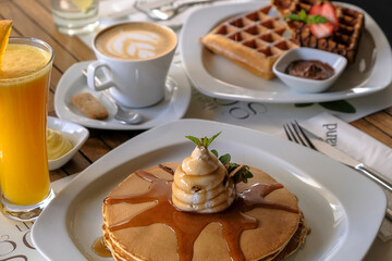 Pancake stack with whipped cream on top with maple syrup drizzling