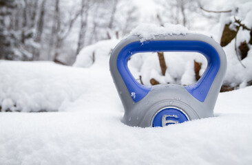 Kettlebell weight in a deep snow. Heavy equipment for home gym workout. Strength training fitness...