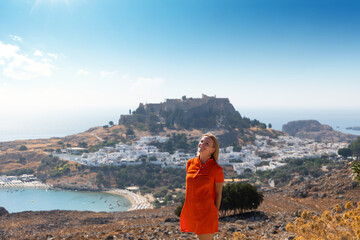 A blonde woman looks at the panorama of Lindos on the island of Rhodes, Greece