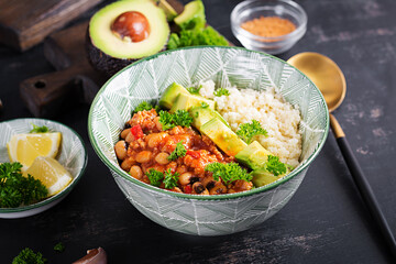 Chili con carne and couscous in bowl on dark background. Mexican cuisine.