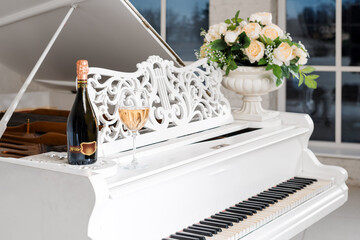 Grand piano in a luxury white classic interior with wine, palms and flowers. © Magryt