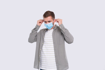 Man Puts on Medical Mask Isolated. Man In Green Shirt Showing How to put on Medical Mask. Health,...