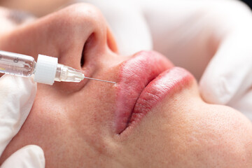 Young lady getting botox injection for bigger, fuller lips. The woman in the beauty salon. Plastic surgery clinic.
