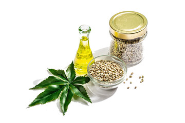 Ripe hemp seeds, oil, and artificial hemp leaf isolated on white background