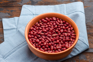 Peanuts in a plate on a wooden background, peanuts