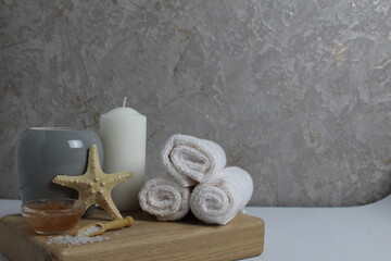 spa massage home care relax. Towels white candles scrub clay salt lie on a tray on a gray background with space for text